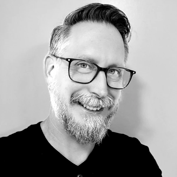 Jay McBride, smiling, in glasses and a dark shirt